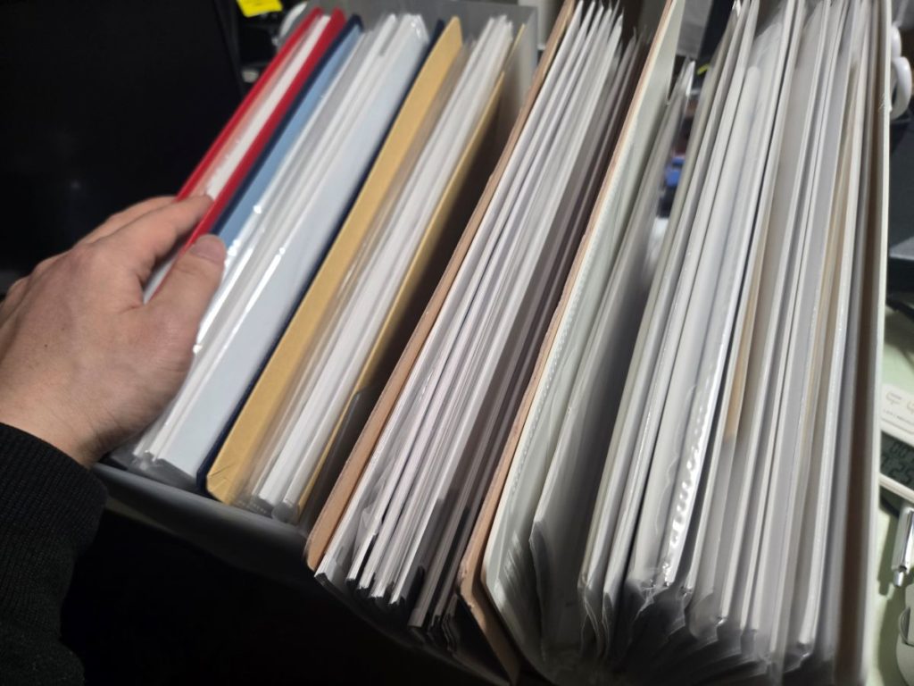 机の横に積まれた大量の学習資料とファイル。著者・桜ソウジが日々向き合っている「重圧」の現場写真。